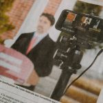 man in black suit jacket holding black camera